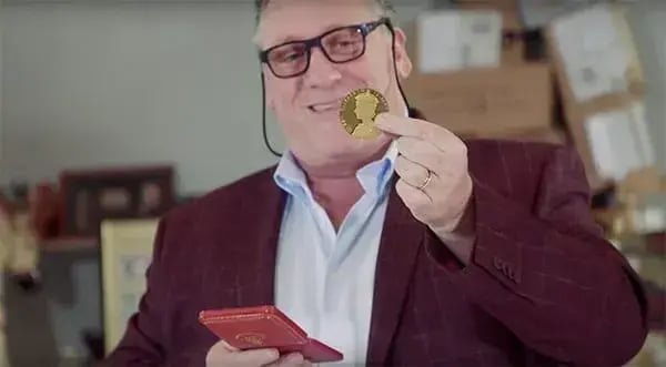 Antony Charman holding a gold coronation medal