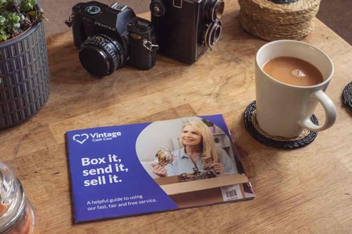 Table with cameras, cup of tea and vintage cash cow leaflet