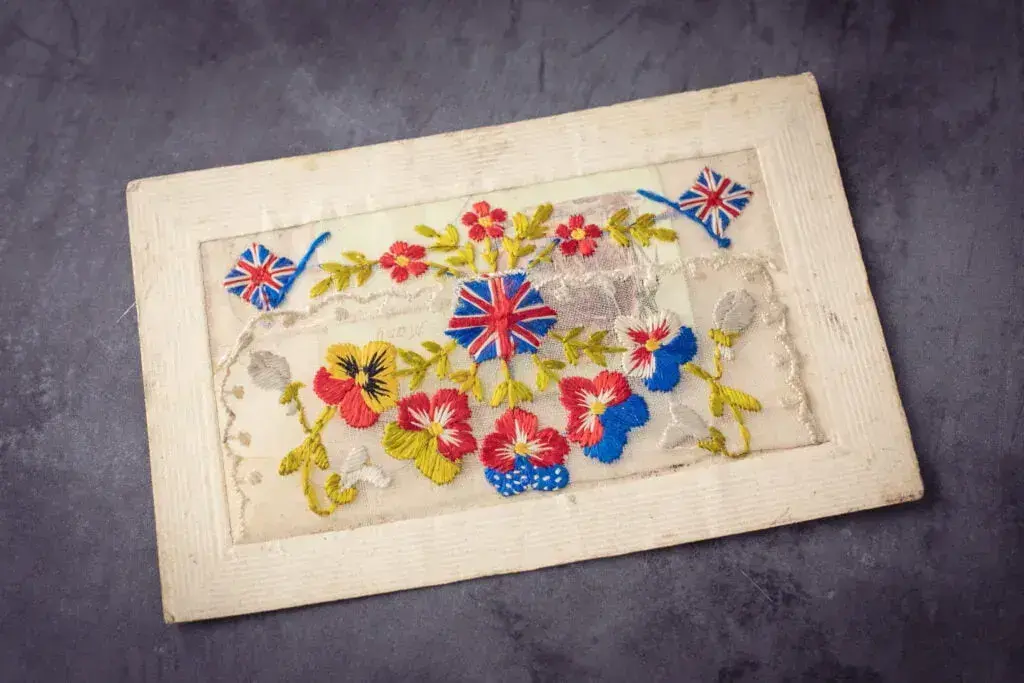 Vintage war postcard with embroidery on lace with British flags and flowers 